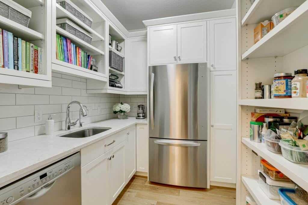 walk in pantry with refrigerator sink dishwasher and lots of cabinets for storage