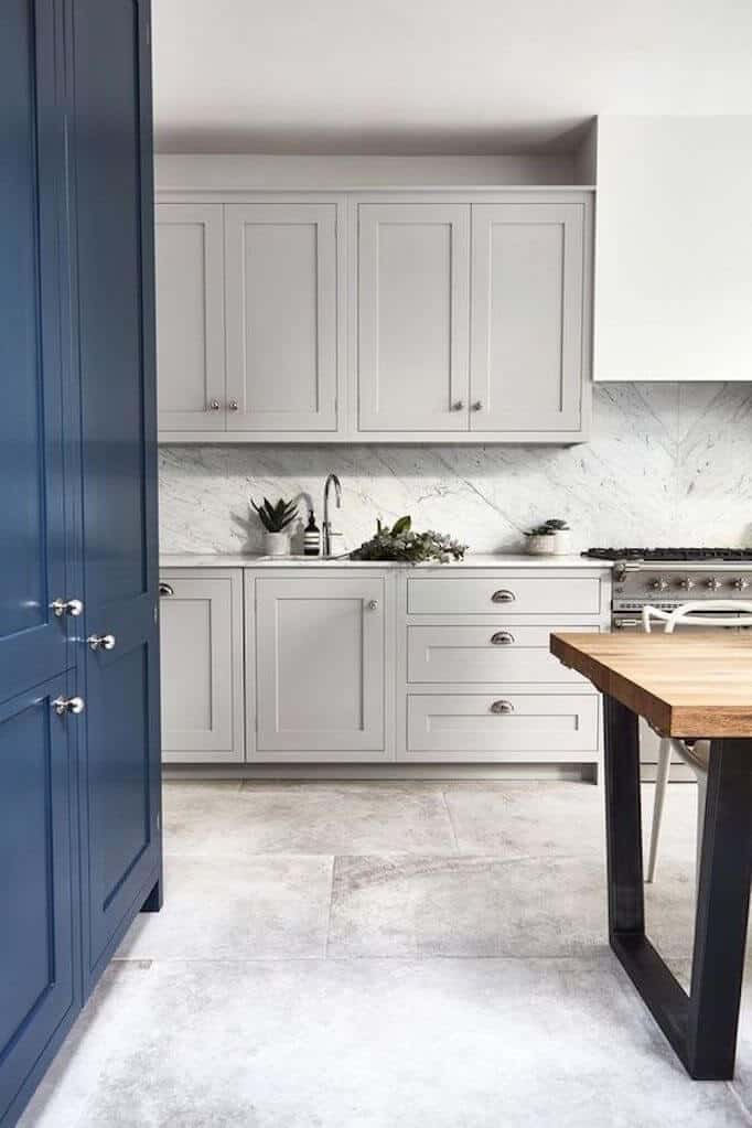 Gray & Navy cabinets modern kitchen with concrete looking floor tiles industrial table