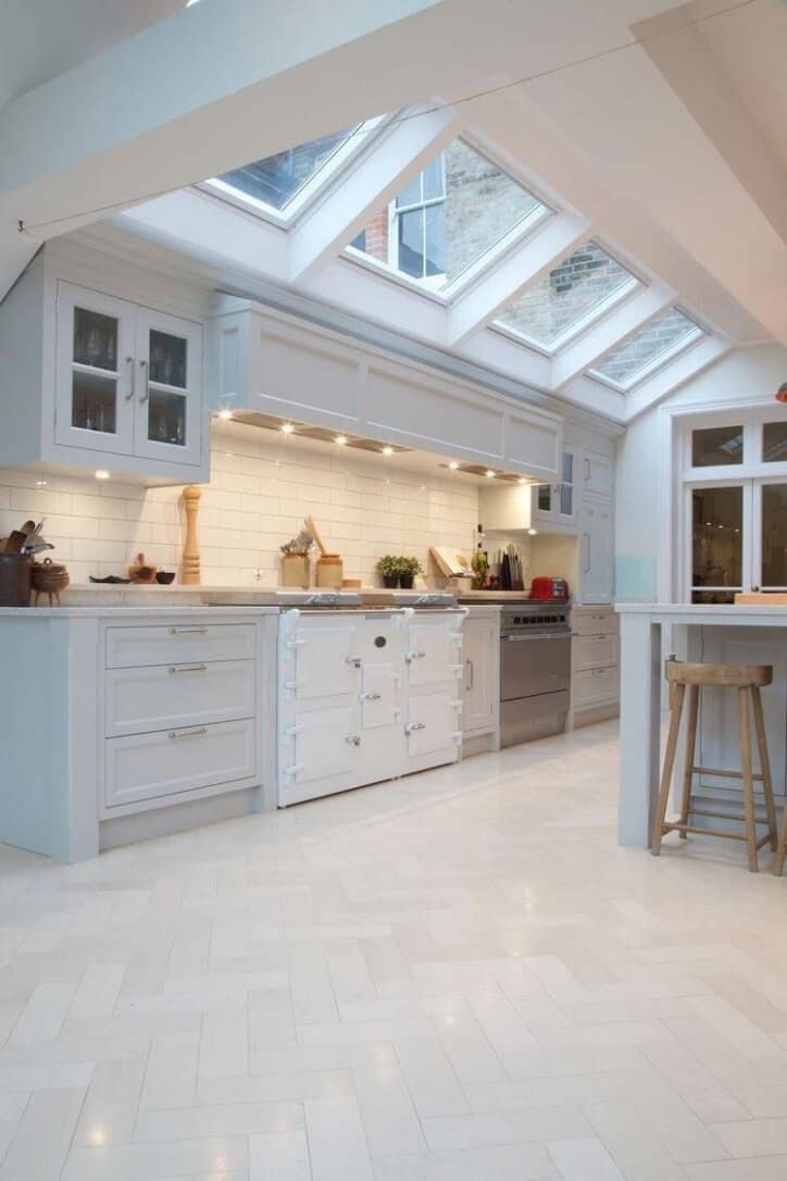 traditional white kitchen with herringbone white tile flooring custom hood and range skylights for added interior light