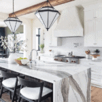 Quartz waterfall island countertop in modern tudor new house with white kitchen and pendant lighting