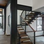 modern floating staircase with wood open treads and a single central metal stringer. has metal railing with top wooden rail. c channel beams supports second floor and add industrial feel to this mountain home