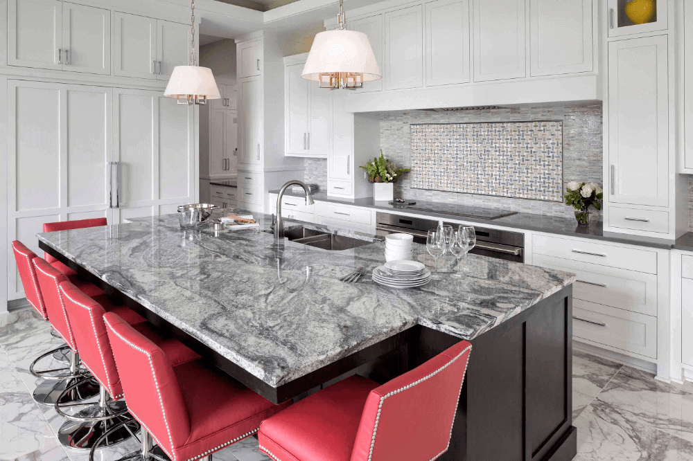 This salone grey and white granite adds the perfect grey cool tone to this traditional yet slightly modern kitchen. This granite has lots of movement, swirls and depth which is a great contrast against the bright red island seating.