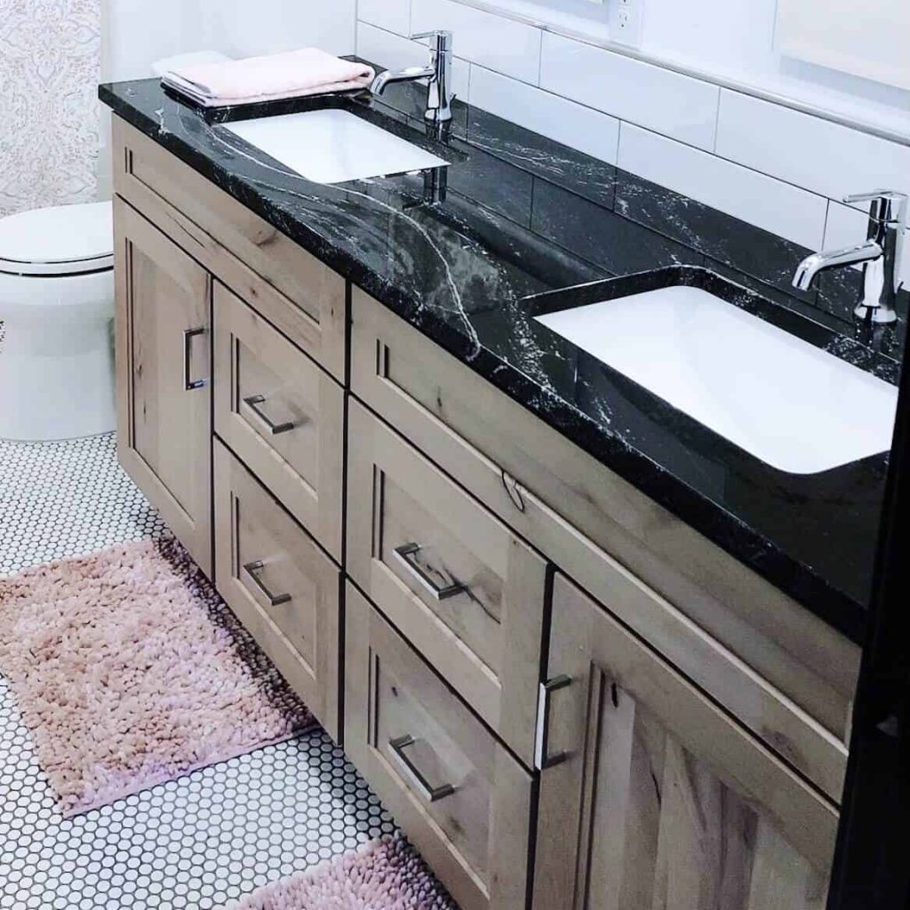 Black Granite with white accents polished bathroom countertop and black and white penny tile with natural alder cabinets