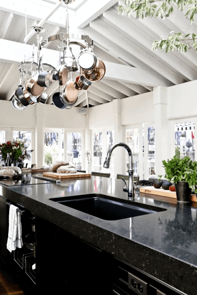 Black granite countertop with thick edge on top of black countertops makes a great contrast to the white walls, ceiling and windows of this open concept kitchen.