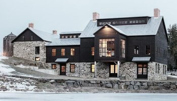 Original Dutch stone and black house is connected with the salvaged vintage barn addition to its right both horizontally and vertically. It contains the entry as well as the stair system which connects three of the four levels of the house. Builder: Gary Lowe. Photo: scott benedict practical(ly) studios. #downleahslane #blackbarn #historicbarn #barndominium #stonehouse #barnhouse #blackhouse #blackexterior #darkhouse #darkexterior #dreamhome #dreamhouse #luxuryhome