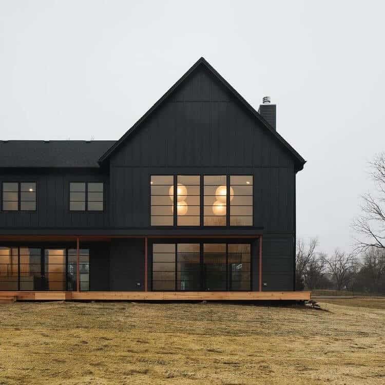 A stunning example of a black modern farmhouse with contrasting beige stone, huge black frame windows, board and batten mixed with horizontal siding and clean lines finish off this modern exterior!! House by M House Development. #downleahslane #blackhouse #modernfarmhouse #modernexterior #darkexterior #darkhouse #dreamhouse #luxuryhome #blackwindows #boardandbatten #exteriorideas #exteriordesign