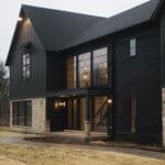 A stunning example of a black modern farmhouse with contrasting beige stone, huge black frame windows, board and batten mixed with horizontal siding and clean lines finish off this modern exterior!! House by M House Development. #downleahslane #blackhouse #modernfarmhouse #modernexterior #darkexterior #darkhouse #dreamhouse #luxuryhome #blackwindows #boardandbatten #exteriorideas #exteriordesign